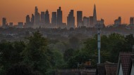 Wimbledon, London in August 2023. An orange sky at sunrise with the skyscrapers of central London.