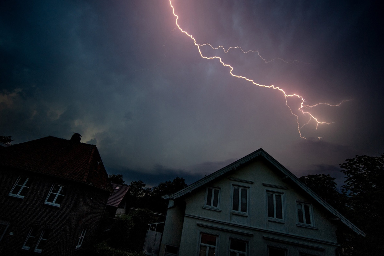 A flash of lightning flashes across the dark evening sky of Oldenburg during a thunderstorm.