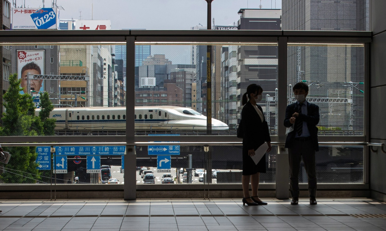 Kurz vor dem Bahnhof Shimbashi in Tokia ist hinter Passanten ein Shinkansen Schnellzug zu sehen.