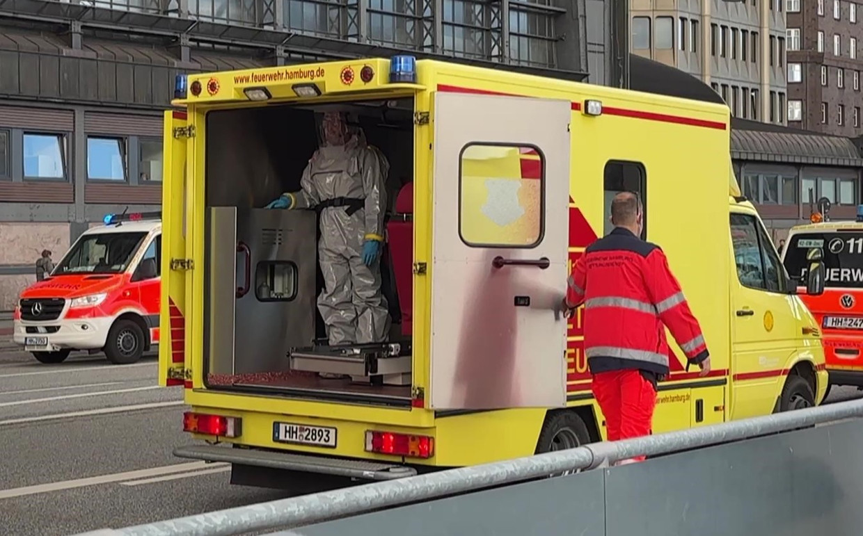 In Schutzkleidung steht eine Einsatzkraft in einem Rettungswagen der Feuerwehr vor dem Hamburger Hauptbahnhof.