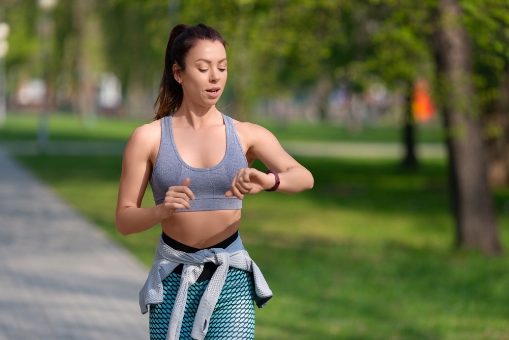 Woman checks her pulse after jogging workout in the park.