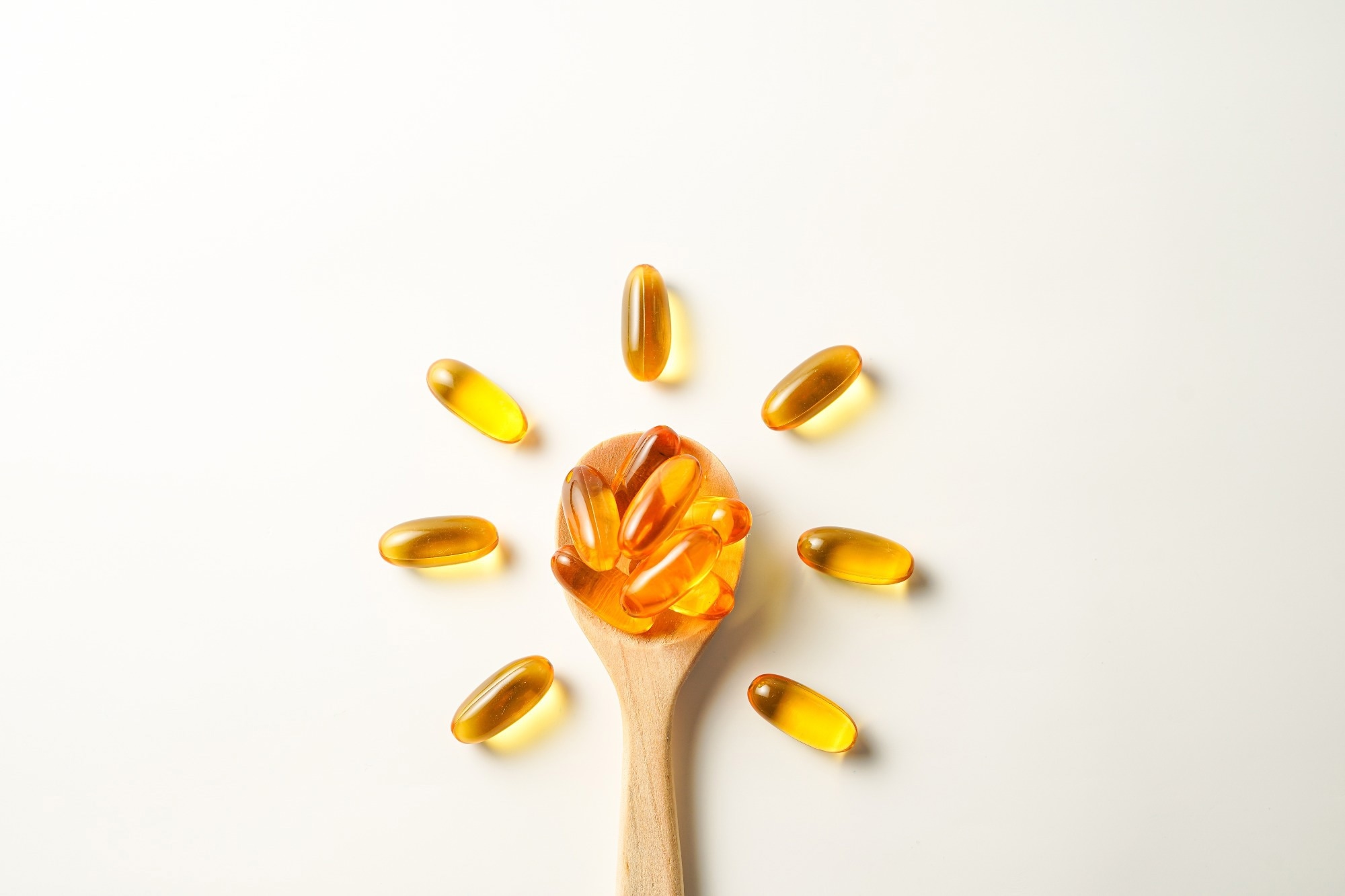 wooden spoon with soft gels, Fish oil capsules, omega 3, omega 9, vitamin D, vitamin E.