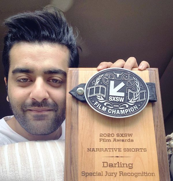 Saim Sadiq holding an SXSW award that his directed short film Darling
