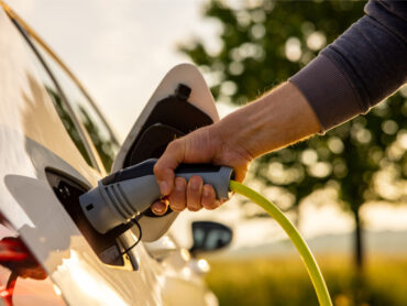 Man inserts a power cord into an electric car for charing