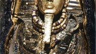 Tutankhamun's mummy after opening the inner coffin.  Under the gold mask, the king wore 26 amulets.  The colors have been digitally reconstructed on this originally black and white photograph.