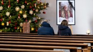 Two churchgoers sit in front of a picture of the late Pope Benedict XVI in St. Oswald's Church on New Year's Eve.