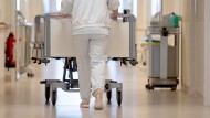 A nurse pushes a hospital bed down a hallway.