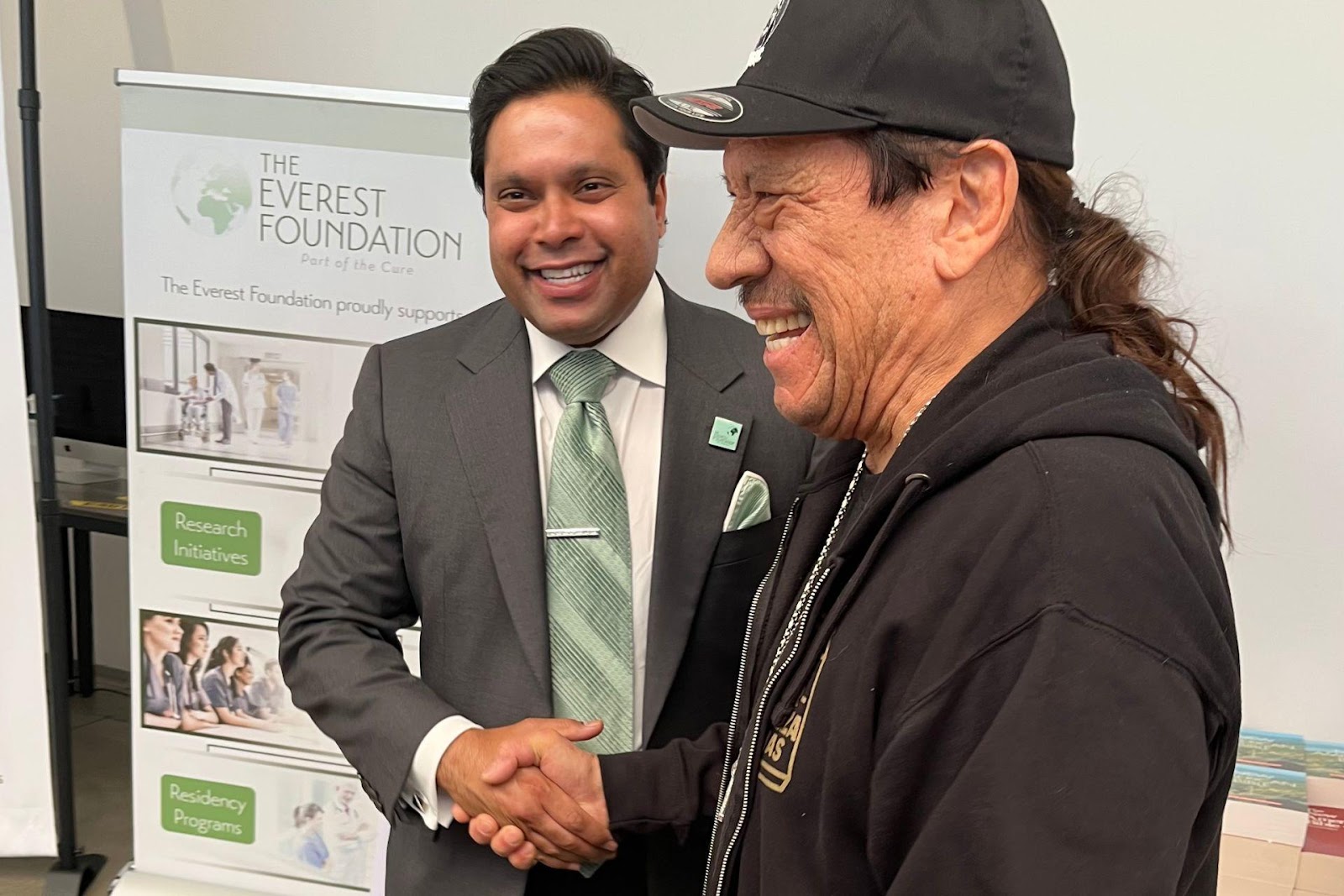 [Alt Text: A picture of Dr. Michael Everest and Danny Trejo shaking hands and smiling at the ‘Bibles and Tacos’ event for homeless veterans.] 