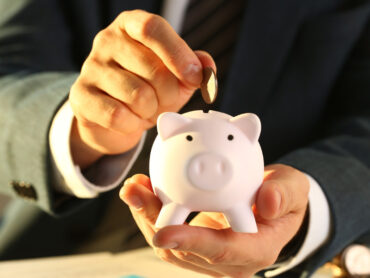 Businessman putting money into a piggy bank