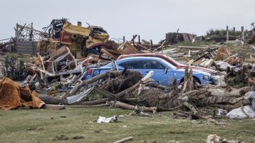 Vehicles and a damaged home in Alberta following a powerful tornado