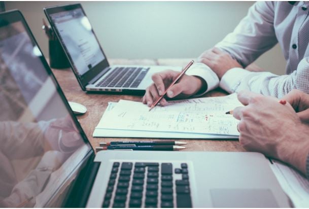 Two people making calculations at a desk - image about whether startups should provide health insurance