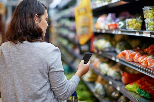 A woman looks for information on her phone at the supermarket.