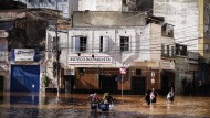 Menschen waten durch ein von heftigen Regenfällen überschwemmtes Gebiet in Porto Alegre.